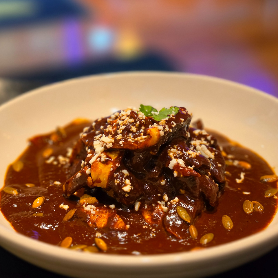 Glazed roasted vegetables piled on a plate with dark sauce, crumbled cheese, pumpkin seeds, and cilantro garnish.